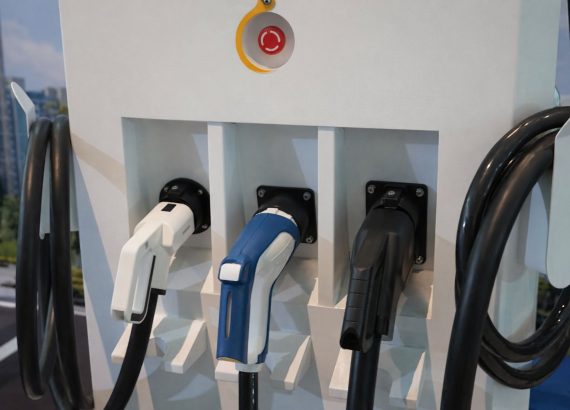 Tre elbilopladere med forskellige stik på en ladestation, klar til brug.