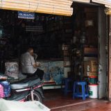 Ejer af en reservedelsbutik sidder ved disken bag en scooter.