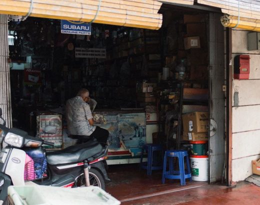 Ejer af en reservedelsbutik sidder ved disken bag en scooter.