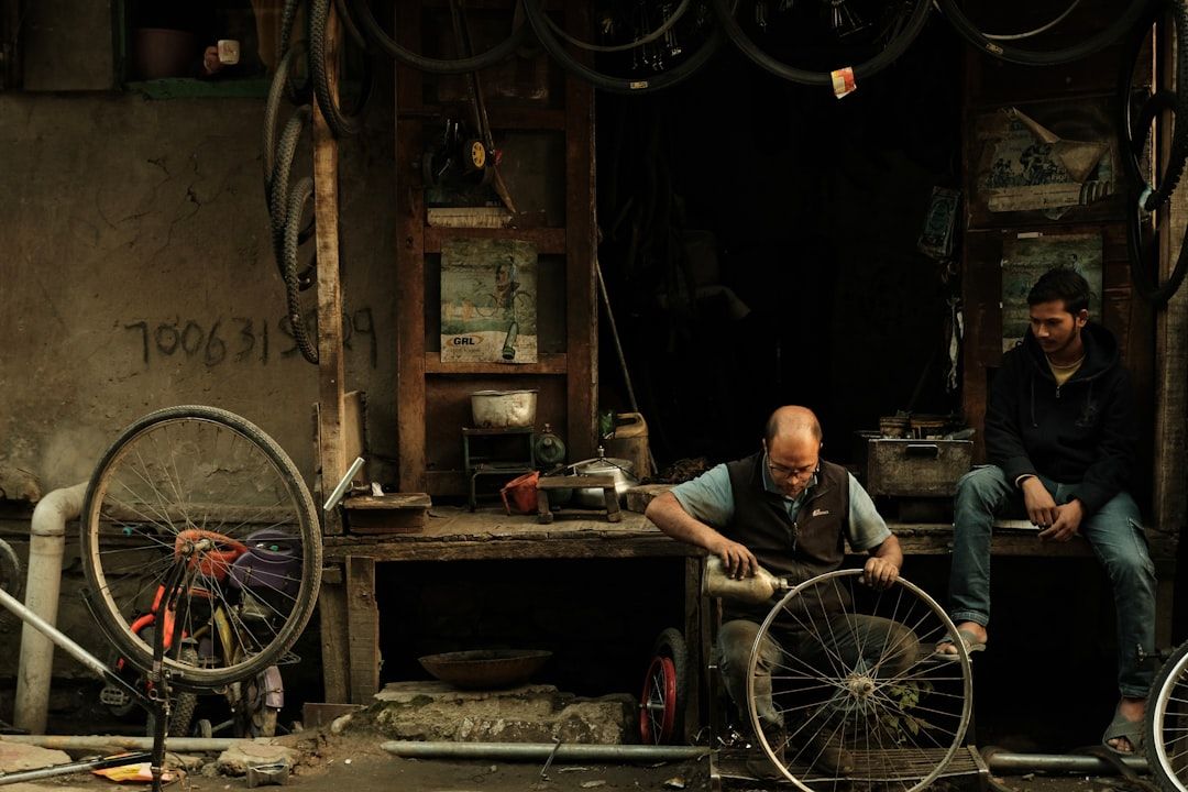 En cykelmekaniker i sit værksted arbejder på et forhjul omgivet af dæk.
