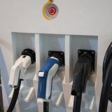 Tre elbilopladere med forskellige stik på en ladestation, klar til brug.