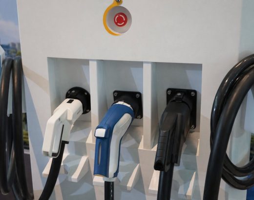 Tre elbilopladere med forskellige stik på en ladestation, klar til brug.